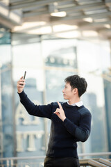 Male manager attending video conference and holding tablet, smatrphone and  cup of coffee in out side office