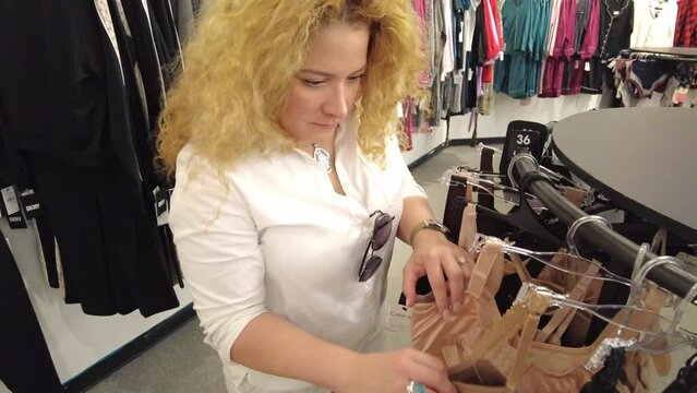 woman carefully looks for a bra size that fits