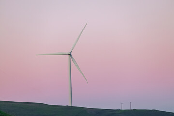 Wind power turbine over the pink colored sky