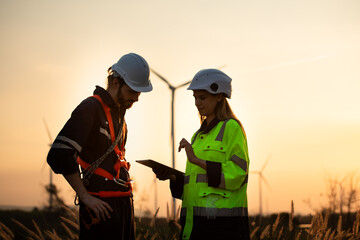 Engineers working on wind farms for renewable energy are responsible for maintaining large wind turbines. Review all tasks of the day while the evening sun shines a beautiful golden light
