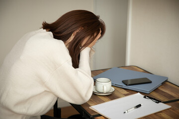 デスクで頭を抱える女性　trouble