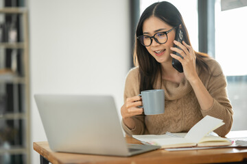 Asian businesswoman sitting and drinking coffee in office