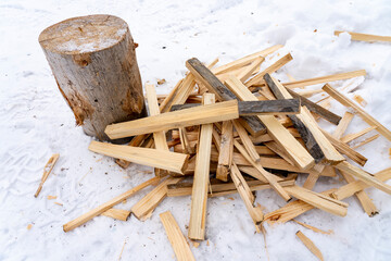 an axe and firewood in the snow, a finely chopped wooden log 