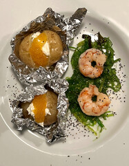 Golden caviar on small baked potatoes and shrimp on seaweed  plate