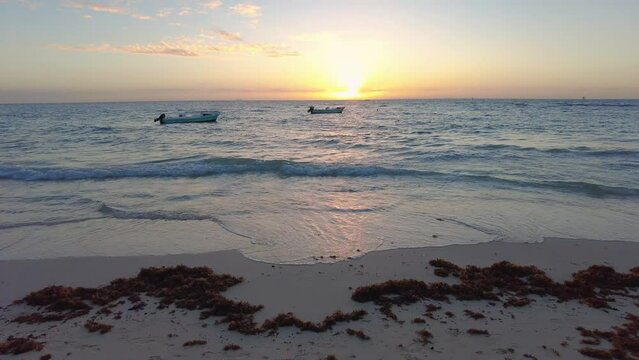 Panoramic video of beautiful golden sunset  at beach with only two boats at sight dancing with the rythm of waves