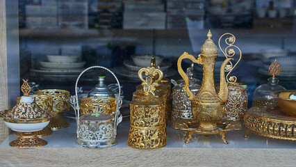 Golden and silver oriental teapot and cup for tea ceremony on showcase
