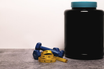 Obraz premium close-up of a Whey protein powder, dumbbells and measuring tape