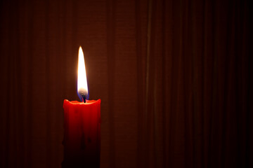 Red candle burning in the dark red background