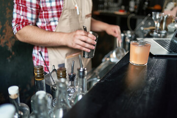 bartender pouring a cocktail from a shaker into a glass.