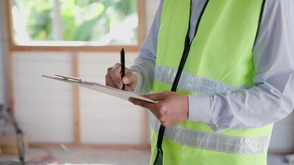 inspector or engineer is inspecting construction and quality assurance new house using a checklist. Engineers or architects or contactor work to build the house before handing it over to the homeowner