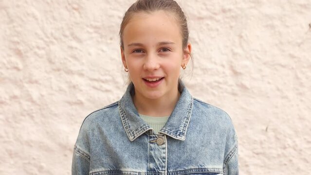 Portrait of a young girl looking at camera and smiling, speaking confidently, girl in jeans shirt telling Yes 