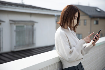 ベランダでスマートフォンをみる女性