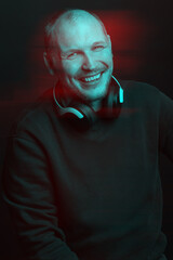 Happy man with sweatshirt and headphones on his neck studio portrait. Model looking at camera with smile. Red and blue color split effect. Black and white with 3D glitch virtual reality effect