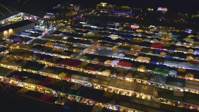 Aerial panning of colorful Asian market tents and food stalls at night