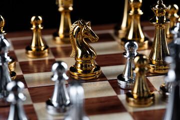 Gold and silver chess figures placed on chessboard