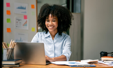 Fototapeta na wymiar Smiling businesswoman working on laptop in modern open office.