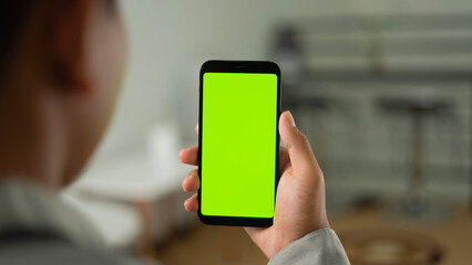 Man holding smartphone in shoulder angle with living room backdrop