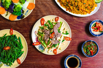 Vietnamese braised beef with papaya, fried rice with pork, salad and sauces on wooden table