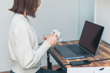 パソコンの前でコーヒーを飲む女性　