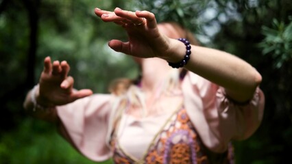Beautiful young gypsy woman dancing with her hands with boho decorations. Portrait of a dancing...