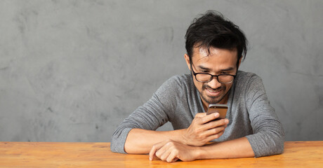Obraz premium lifestyle young man using mobile phone with vintage empty table and wall loft background