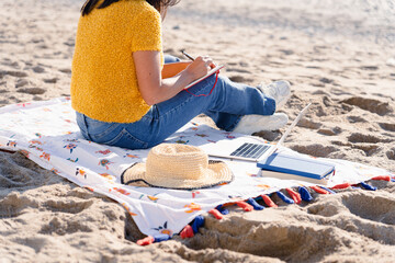 Latin woman taking note and getting inspiration for a day at work on the beach in Spain
