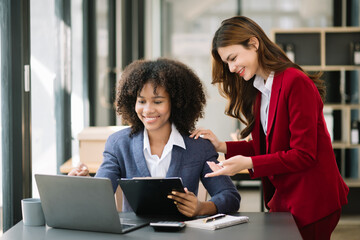 Two businesswoman discuss investment project working and planning strategy with tablet laptop computer in modern office..