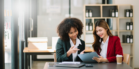 Businesswomen work and discuss their business plans. A Human employee explains and shows her colleague the results paper in modern office..