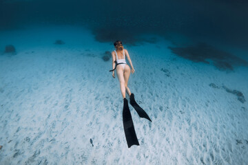 Attractive lady freediver glide underwater on the deep. Freediving with sexy woman in blue ocean