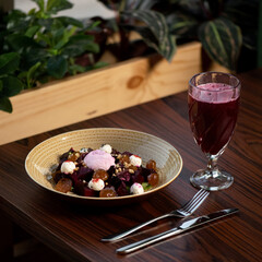 Salad of boiled beets, dried apricots, mozzarella, nuts, herbs. Plate with dish, knife, fork, glass...