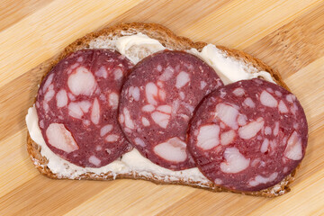 Open sandwich with smoked-cured sausage and butter, top view