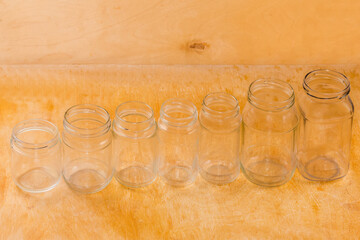 Row of empty glass jars different sizes on wooden surface