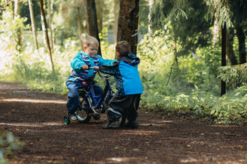 little boy teaching brother to ride bicycle