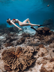 Sporty sexy woman underwater over corals in transparent blue ocean. Freediving with beautiful girl in tropical sea