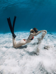 Freediver lady in bikini with sand in hands over sandy bottom. Freediving in tropical blue ocean with attractive woman