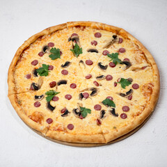 Pizza with sausages, mushrooms and cheese cut into pieces, garnished with parsley. Italian Cuisine. Top view. Isolate on white background. Copy space. 