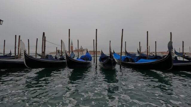 Gondolas are tied on the pier in the open sea in the city of Venice near the main square . Italy