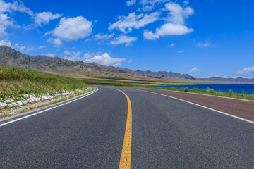 Fototapeta na wymiar Empty asphalt road and lake with mountain natural scenery in Xinjiang, China.