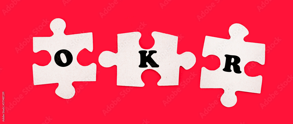 Poster three white jigsaw puzzles with the text okr objective key results on a bright red background.