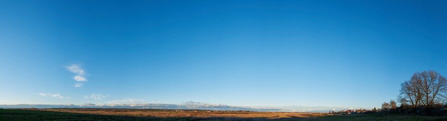 A beautiful summer panoramic view of a cloudless and blue sky over a green valley