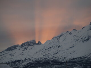 Rays of sunlight coming up back mountains in Northern Norway