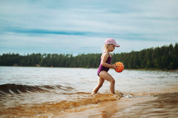 cute little girl playing with rubber ball in sea