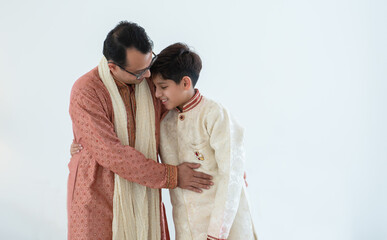 Happy Indian handsome teenage son hugging father standing spending time together, wearing traditional clothing. Family bonding concept. White background