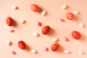 Red easter eggs with colorful candies on pink background. 