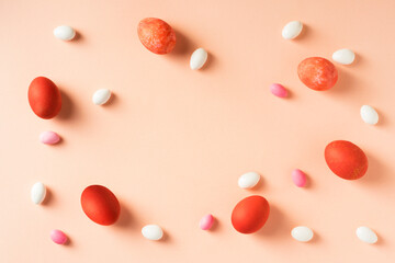 Red easter eggs with colorful candies on pink background. Blank copy space on center.