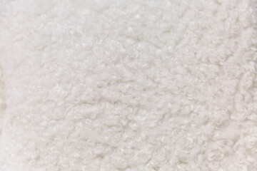 Curly surface of white bouclé fabric. Interior design and textiles. Close-up. Space for text.