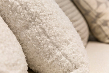 Sofa cushions in light bouclé fabric. Fashionable interior design, decor and textiles. Close-up. Side view. Selective focus.