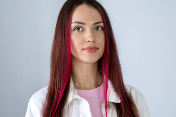 Headshot of a funny rebellious young woman with bright pink hair looking straight at the camera....