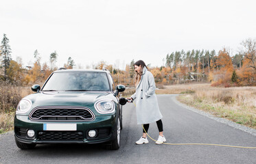 woman plugging in her electric car Mini Countryman in the countryside