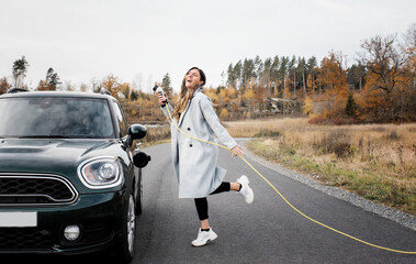 woman dancing playfully whilst plugging in an electric car